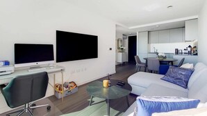 Un salon moderne avec un canapé, une table basse et un bureau avec un ordinateur.