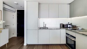 Une cuisine moderne avec des meubles blancs, un plan de travail en granit et des appareils électroménagers en acier inoxydable.