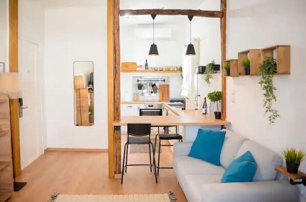 Un salon moderne avec un canapé, un coin repas et une cuisine en arrière-plan.