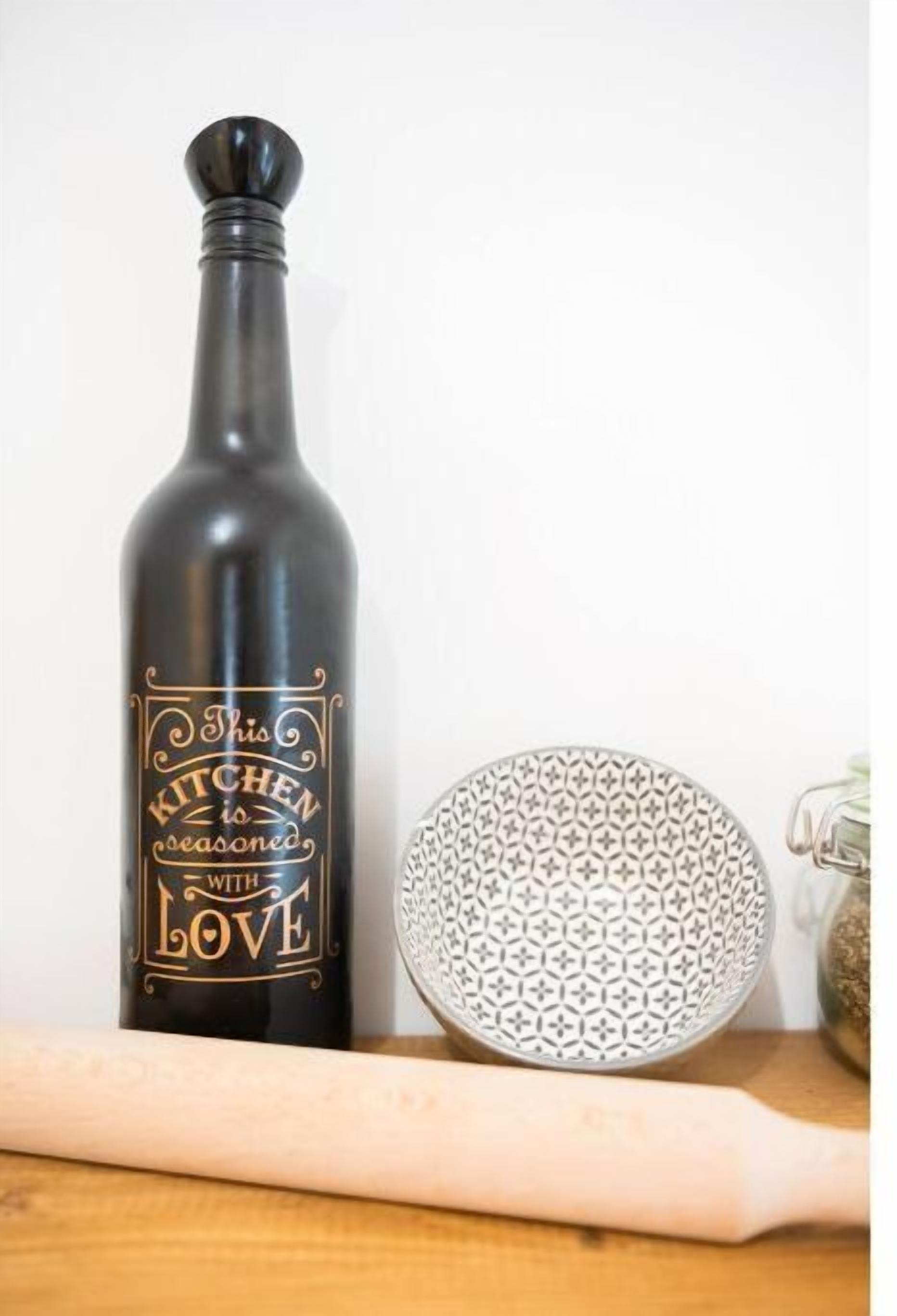 Uma garrafa escura com uma etiqueta que diz 'Esta cozinha é temperada com amor' e uma tigela estampada sobre uma superfície de madeira.