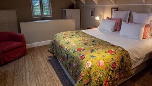 A bedroom with a bed, a nightstand, a red chair, and a window. - Cook’s Cottage, Franschhoek village (Franschhoek)