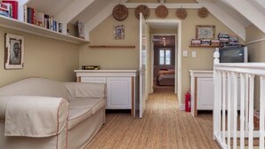A narrow hallway with a white railing, a bed on the left, and a television on the right. - Cook’s Cottage, Franschhoek village (Franschhoek)