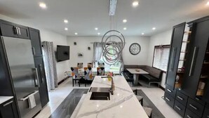 Una cocina moderna con una isla central, armarios oscuros y un comedor con mantel estampado.