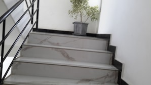 A staircase with marble steps and a metal railing, leading to a landing with a potted plant. - Danakil Hotel (Addis Ababa)