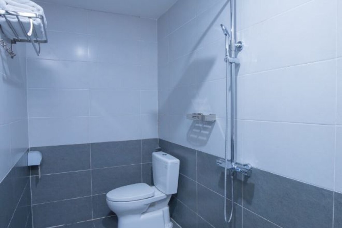 A bathroom with a toilet, a shower, and a towel rack.