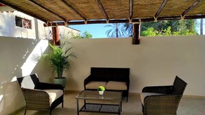 An outdoor patio with wicker furniture, a glass coffee table, and a potted plant. - 3 Bedrooms Home 5 min Walking Distance to El Malecon (La Paz)