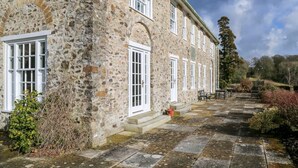 Un bâtiment en pierre doté de nombreuses fenêtres et d’une cour pavée de pierres.