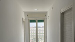 A corridor with a view of buildings through a glass door. - B&B HoMa (Naples)