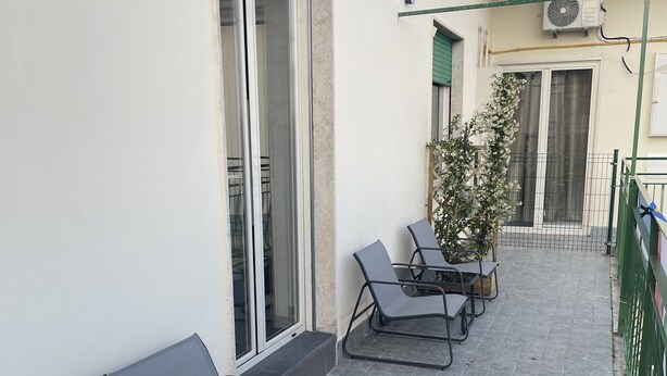 A balcony with a grey sofa, two lounge chairs, and a potted plant. - B&B HoMa (Naples)