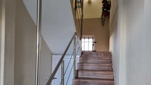 A wooden staircase with metal railings leading to a door with a green exit sign. - Doux Réveil (Cap Malheureux)