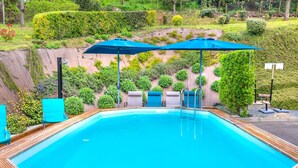 A swimming pool with blue umbrellas, lounge chairs, and a wooden deck. - Gîte du Thouet - Appt avec piscine partagée (Montreuil-Bellay)