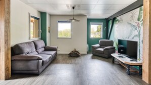 Ein Wohnzimmer mit grauem Sofa, braunem Sessel und Couchtisch aus Holz.