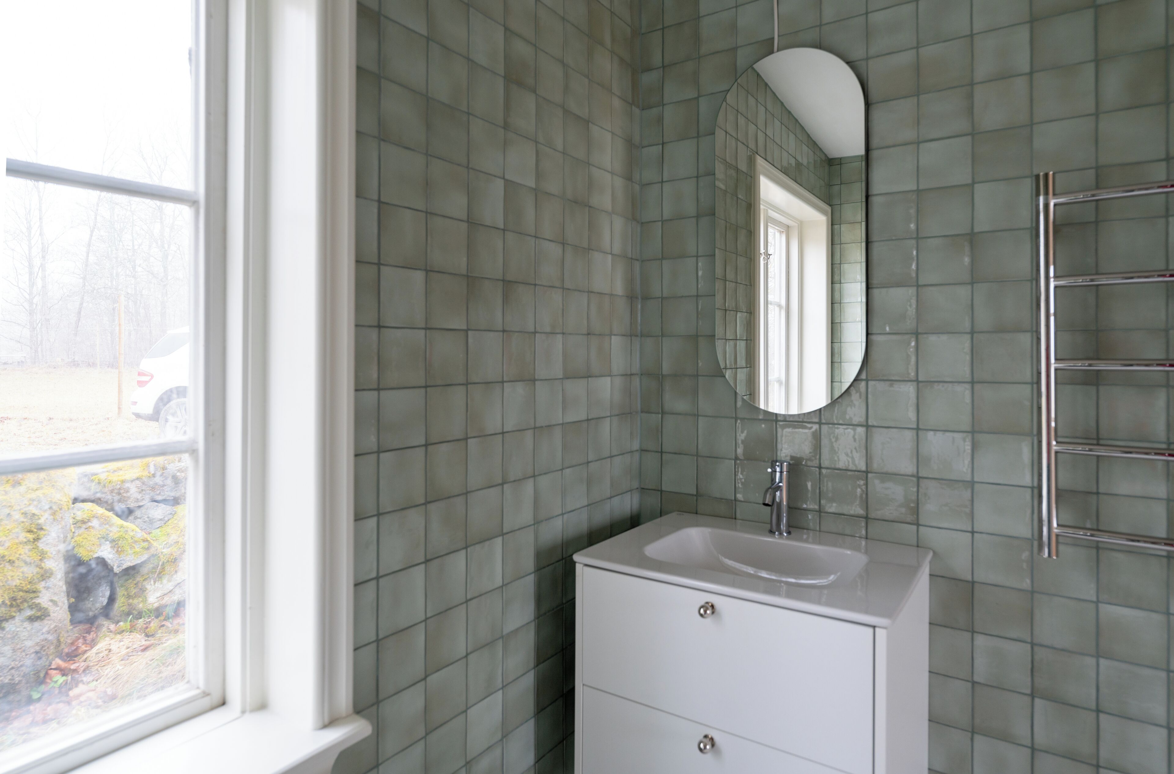 A bathroom with a white vanity, a mirror, and a towel rack.