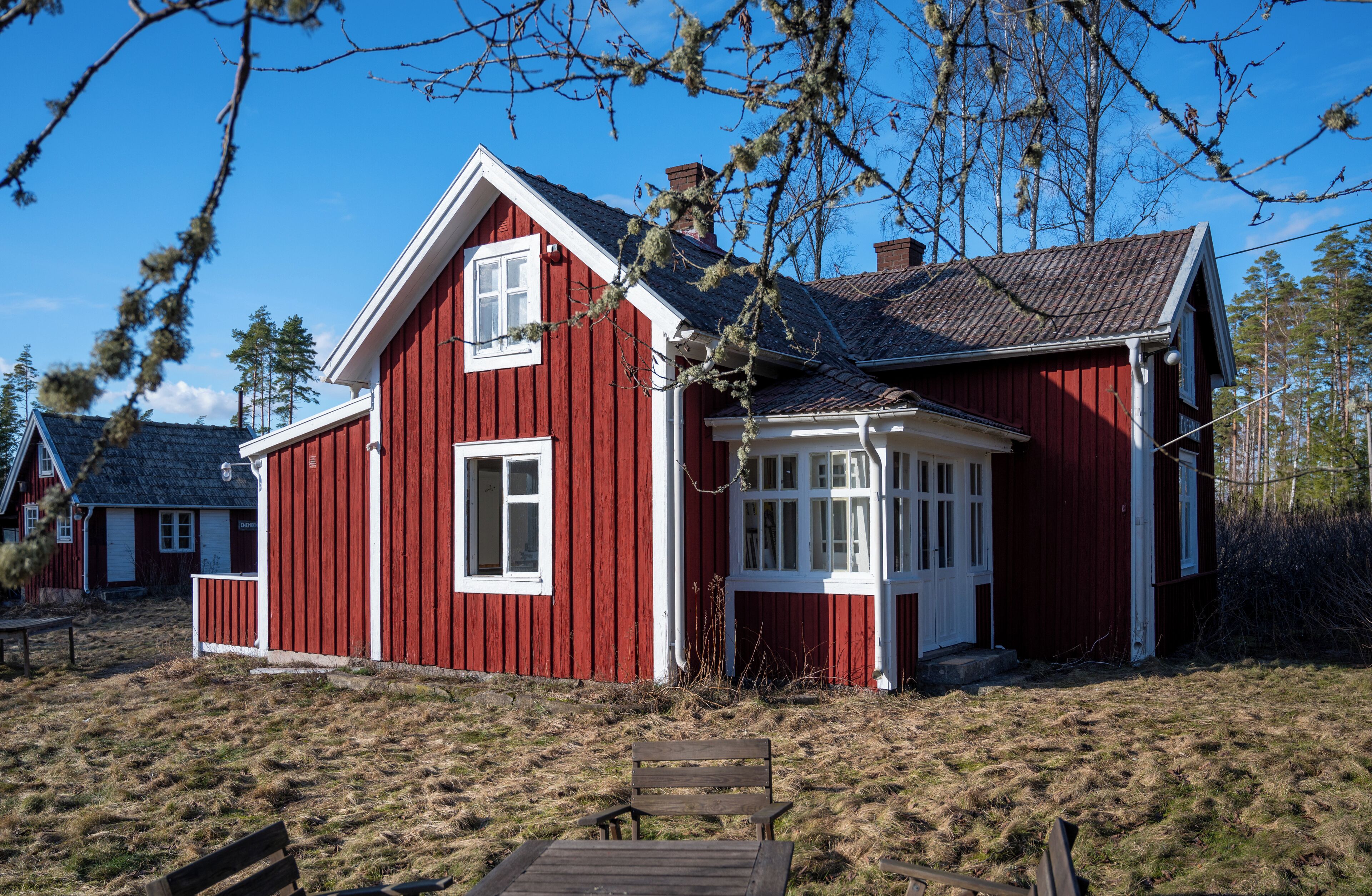 Une maison en bois rouge, avec un toit à pignon et des éléments décoratifs blancs.