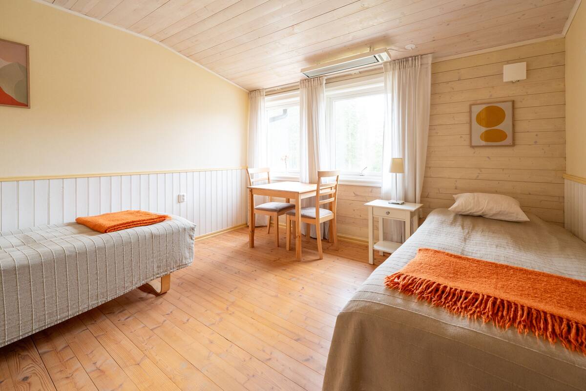 A room with two beds, a desk, and a chair.