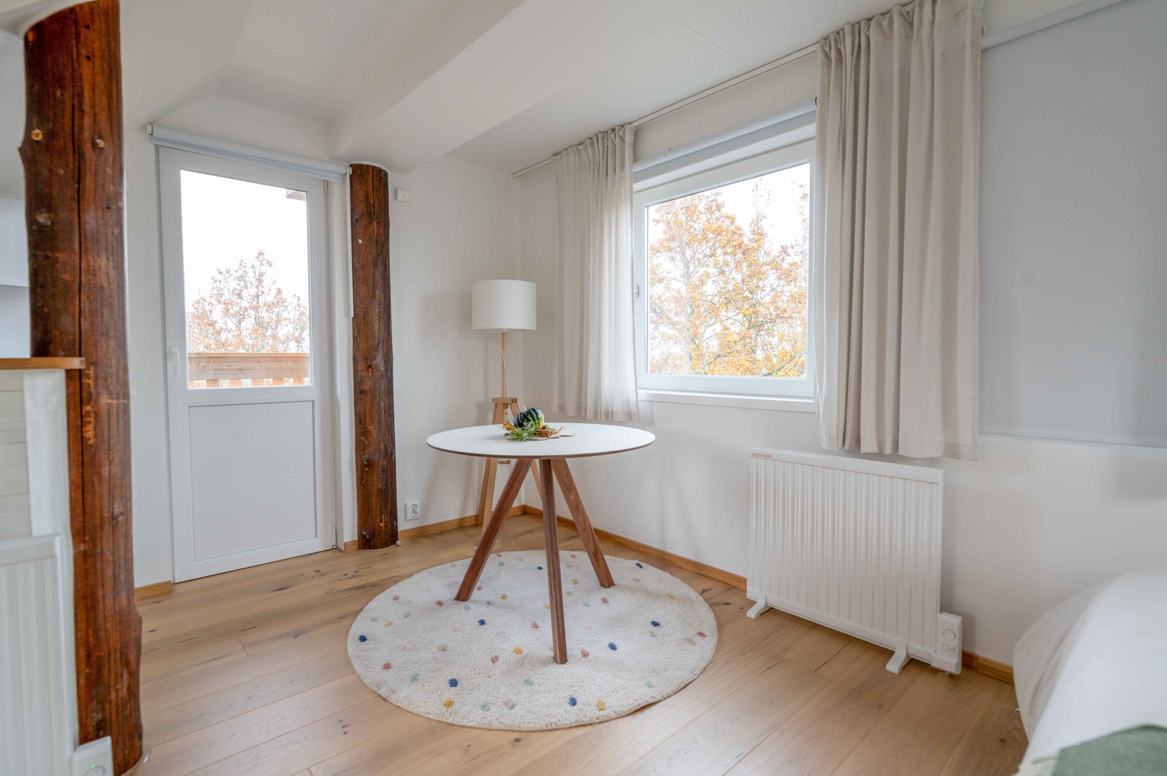 Ein Zimmer mit rundem Tisch, Lampe und Heizkörper.