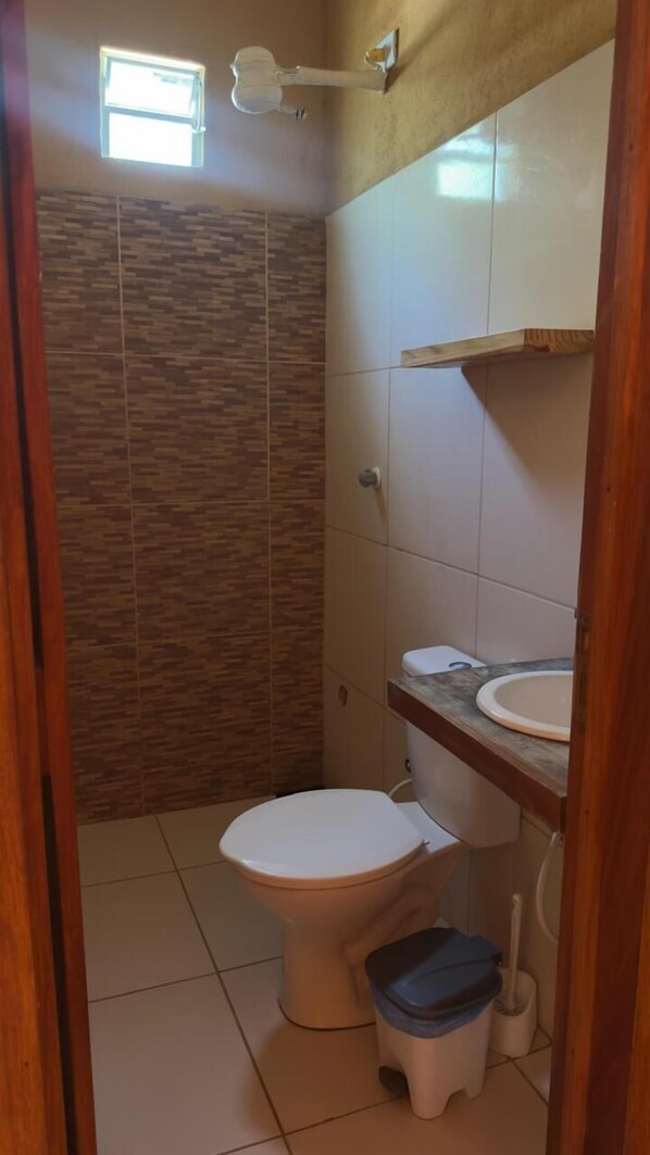 A small bathroom with a toilet, a sink, and a shower area.