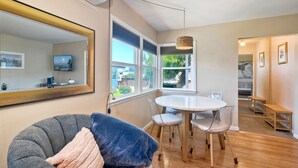Een moderne woonkamer met een grijze bank, een witte eettafel en een grote spiegel.