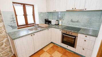 A kitchen with a sink, a stove, and a window with curtains.