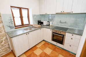 Eine Küche mit Spüle, Herd und einem fensterbedeckten Fenster.