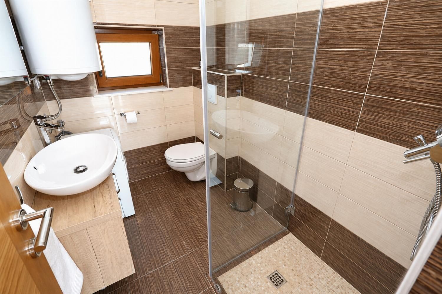 A modern bathroom with a glass shower enclosure, a white sink, and a toilet.