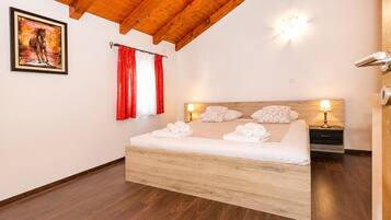 A bedroom with a wooden bed, a nightstand, two wall-mounted lamps, and a painting on the wall.
