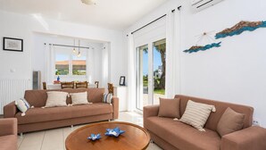 Una sala de estar moderna con dos sofás, una mesa de centro y vistas al exterior a través de amplios ventanales.