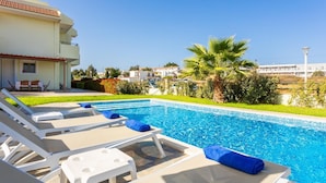 Piscina con sillas de descanso y vista a una zona residencial.