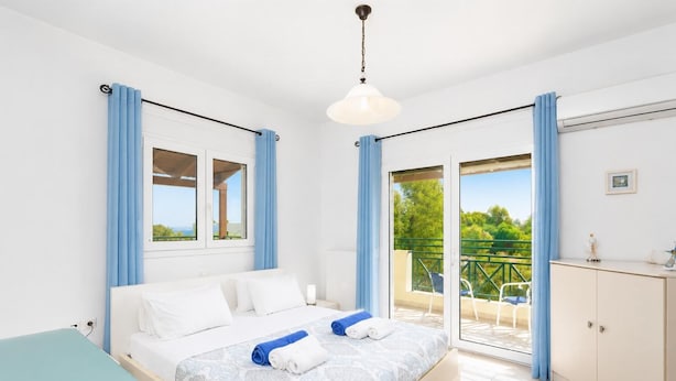 Un dormitorio con cama, escritorio, armario y balcón con vistas.