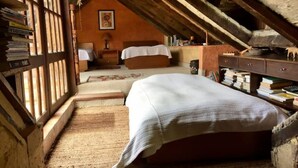 A rustic attic bedroom with a large bed, wooden beams, a bookshelf, and a desk. - Embalse del Sisga- El Cobijo Casa de Campo (Cundinamarca)