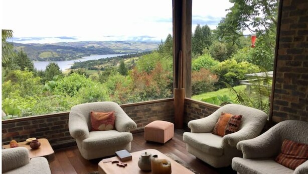 A cozy seating area with two armchairs and a small table, overlooking a scenic landscape with a lake and hills. - Embalse del Sisga- El Cobijo Casa de Campo (Cundinamarca)