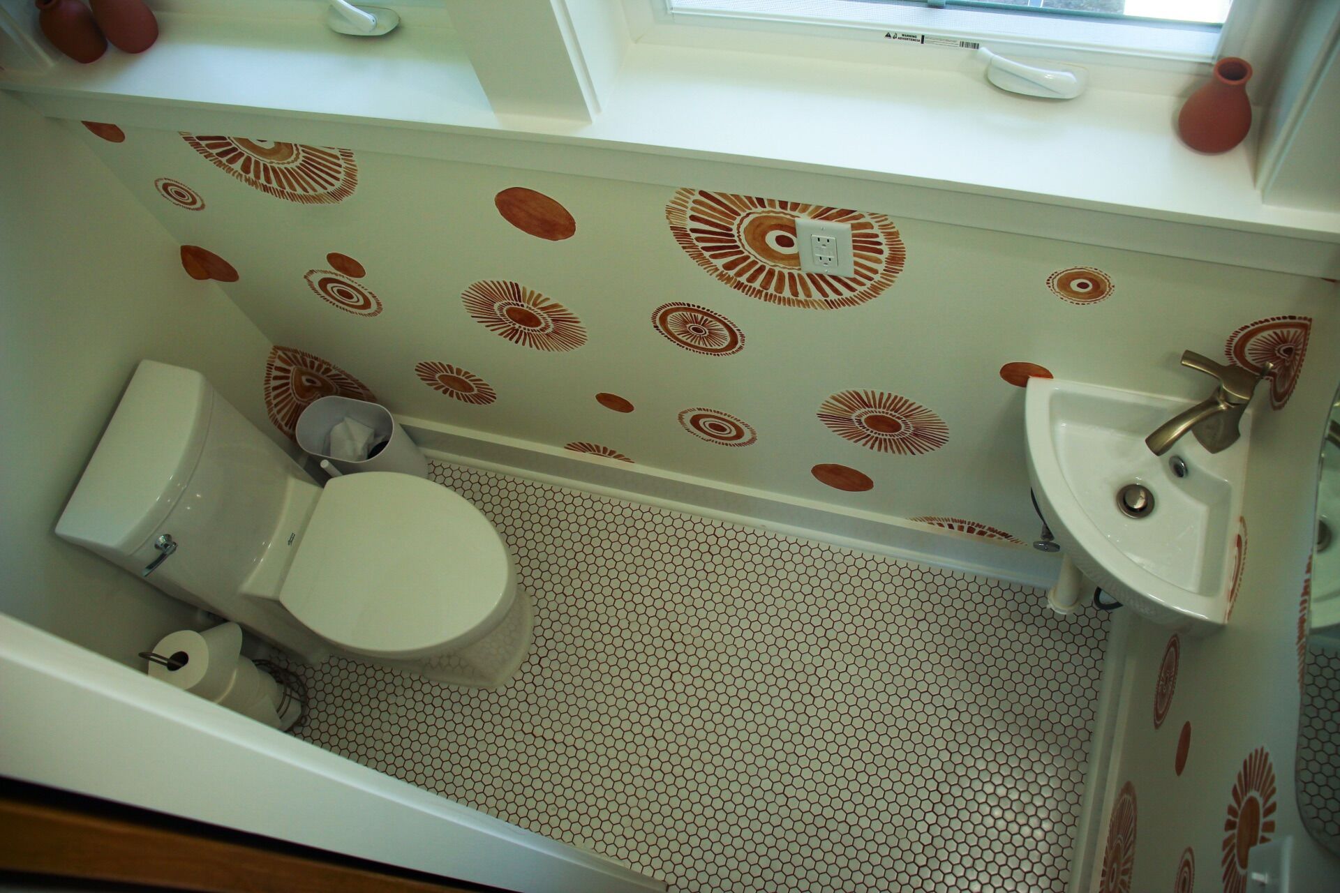 A bathroom with a toilet, sink, and bathtub. The walls have a patterned design.