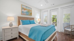 Quarto com cama, mesas de cabeceira, ventilador de teto e um quadro.