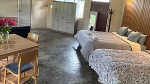Een slaapkamer met een bed, een bureau met stoel, een kledingkast en een kapstok.