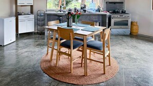 Een moderne keuken met een eethoek, een kleine koelkast en een gasfornuis.