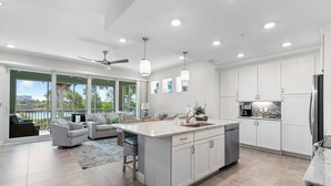 A spacious kitchen with a large island, white cabinetry, and a view of the outdoors. - Otter Lagoon at One Particular Harbour  379-103 Lagoon Views · Gaming · 3BR (Bradenton)