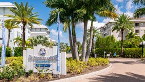 A sign for One Particular Harbour in Margateville, with a paved driveway and palm trees. - Otter Lagoon at One Particular Harbour  379-103 Lagoon Views · Gaming · 3BR (Bradenton)