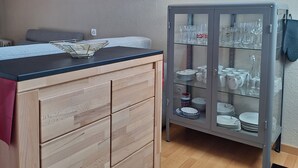 Keittiössä on puiset kaapit, työtaso ja lasiovilla varustettu vitriini, jossa on esillä astioita.