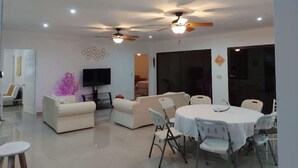 A modern living room with a dining area, ceiling fans, recessed lighting, and a flat-screen TV. - Linda Vista (Tronadora)