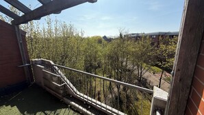 A balcony with a metal railing overlooking a courtyard with trees and a building in the background. - Apartment in Laatzen! contactless check-in 11P (Laatzen)
