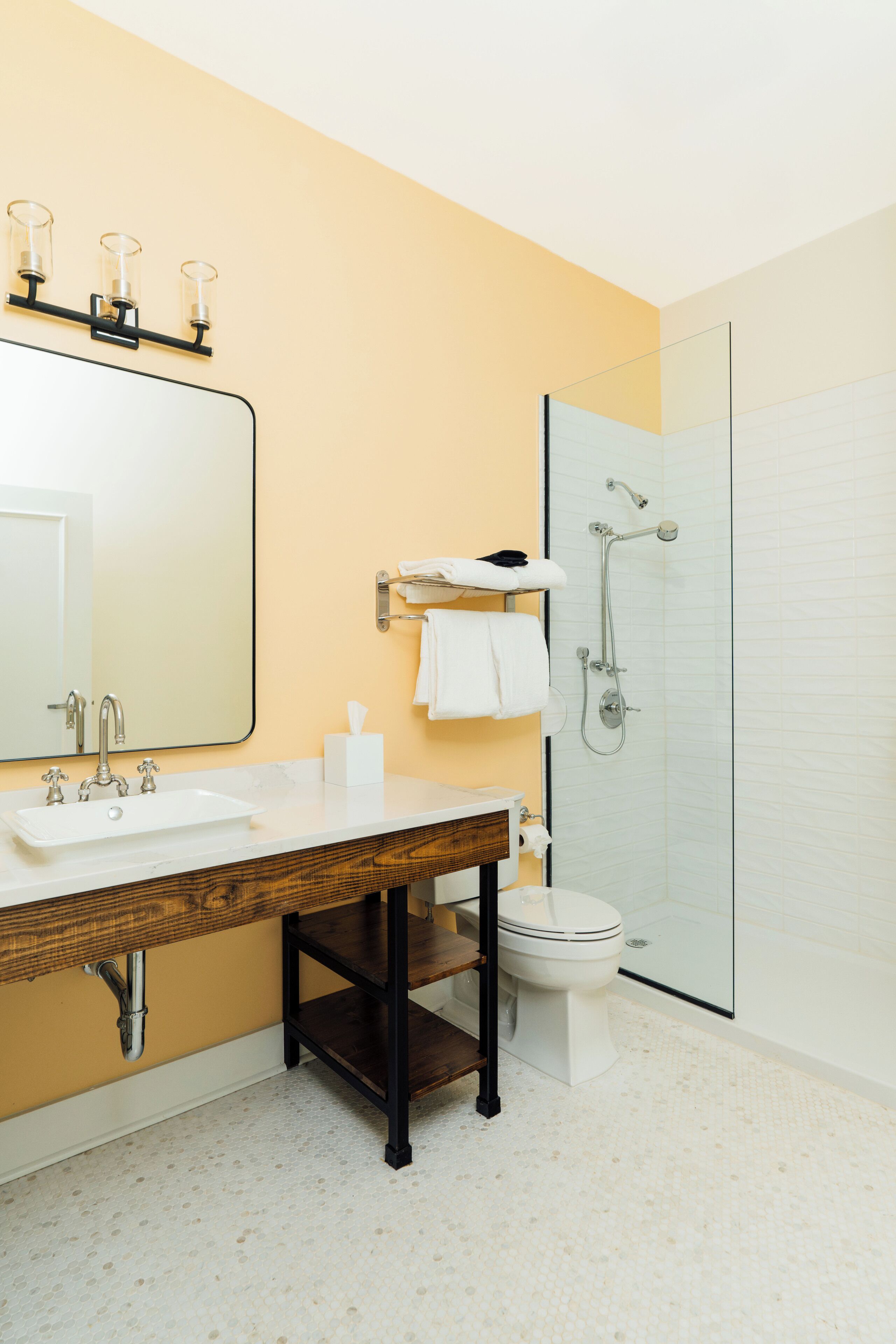 A bathroom with a sink, mirror, toilet, and shower.