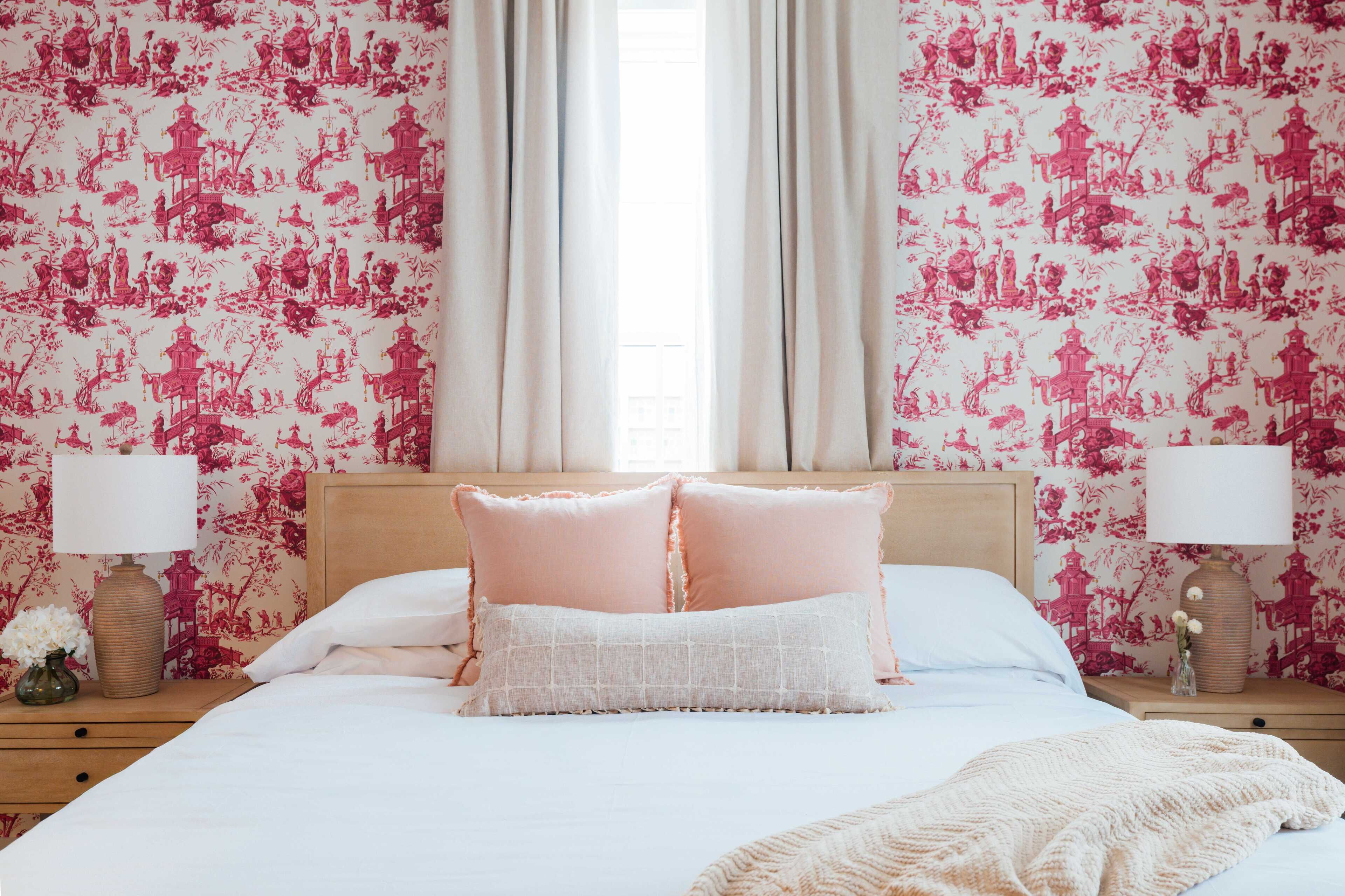 A bedroom with a bed, two nightstands, a window with curtains, and floral wallpaper.