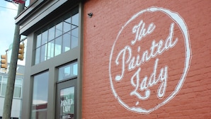 A hotel with a red exterior, a large window, and a sign that reads 'The Painted Lady Hotel.'