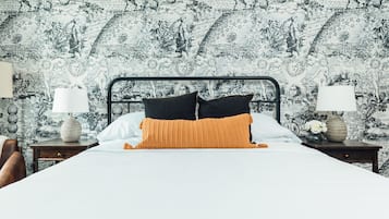 Un dormitorio con una cama, dos mesitas de noche y un papel pintado estampado.