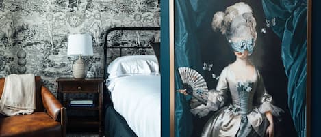 Een slaapkamer met een bed, nachtkastje en een lijst met een portret.