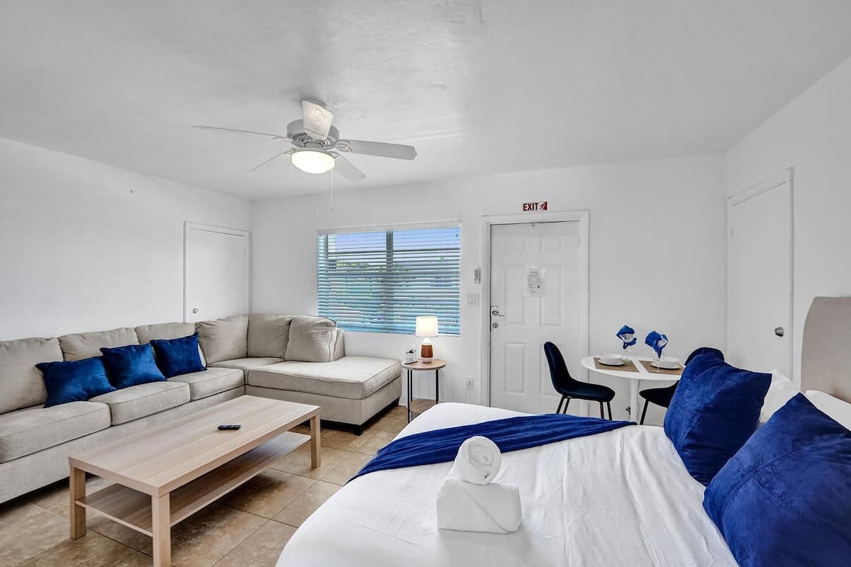 Une pièce moderne et bien éclairée, avec un canapé, un lit, une petite table et un ventilateur de plafond.