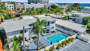 Un hotel moderno con piscina en la azotea, rodeado de palmeras y vistas al océano.