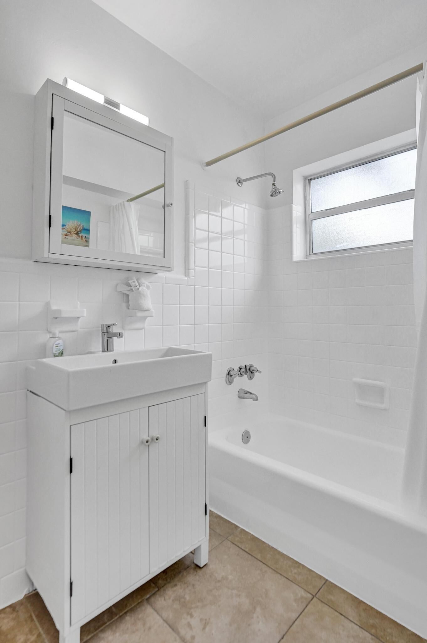 Un baño con lavamanos blanco, espejo y bañera.