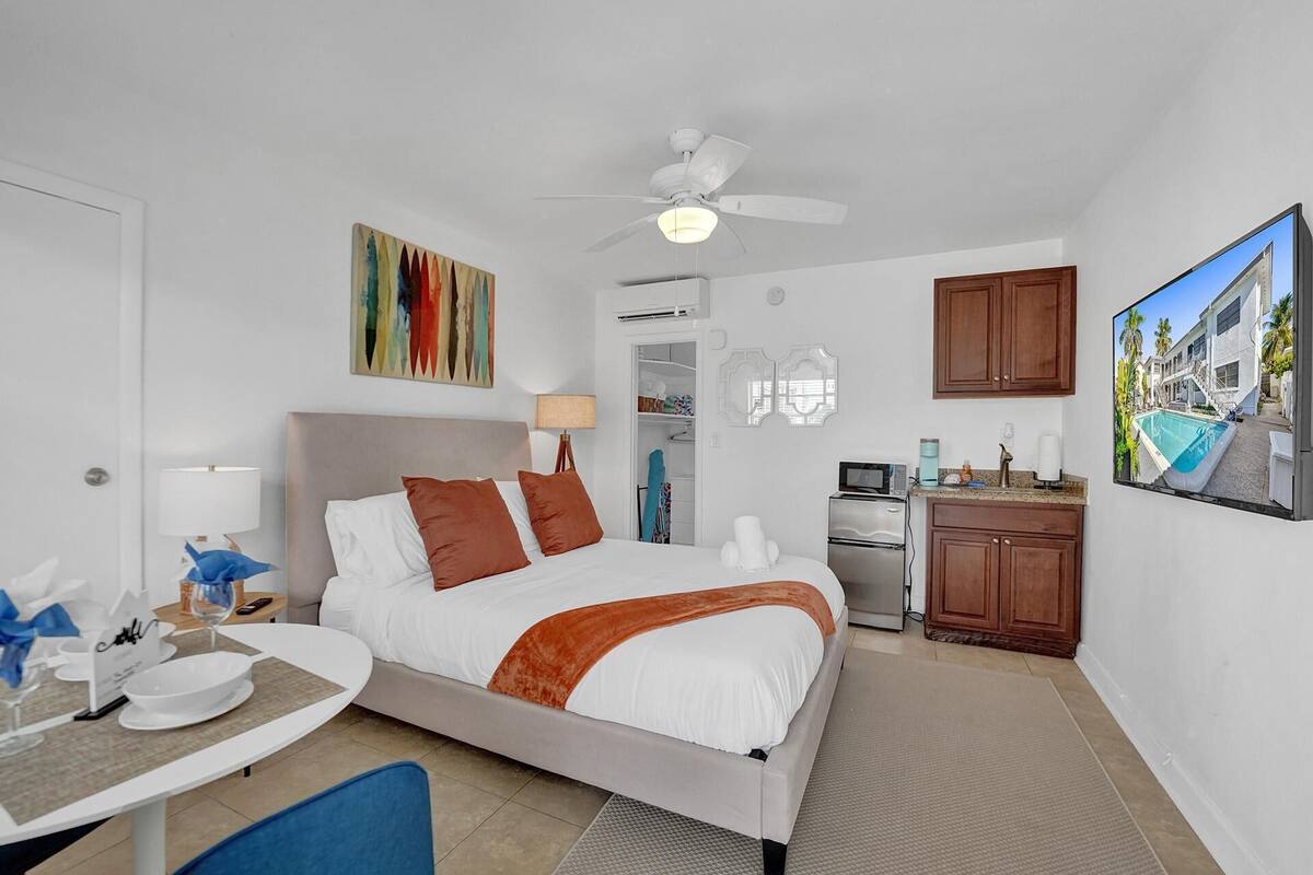 Une chambre d’hôtel équipée d’un lit, d’un bureau, d’une kitchenette et d’une grande fenêtre.