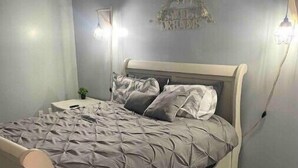 A bedroom with a bed, grey walls, and wooden flooring. - Remodeled duplex near coliseum (Greensboro)